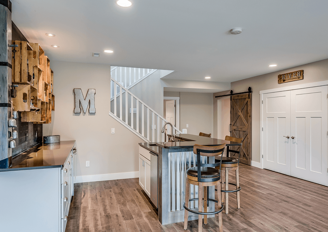 a photo of a finished basement with tile hardwood floors, a bar, and a kitchen island surrounded by three chairs