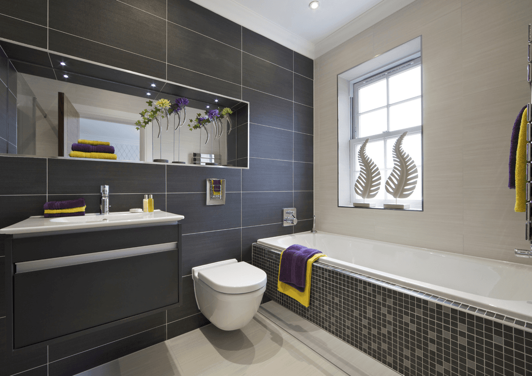 a photo of a renovated bathroom with grey tiles on the walls and grey backsplash tiles on the bathtub